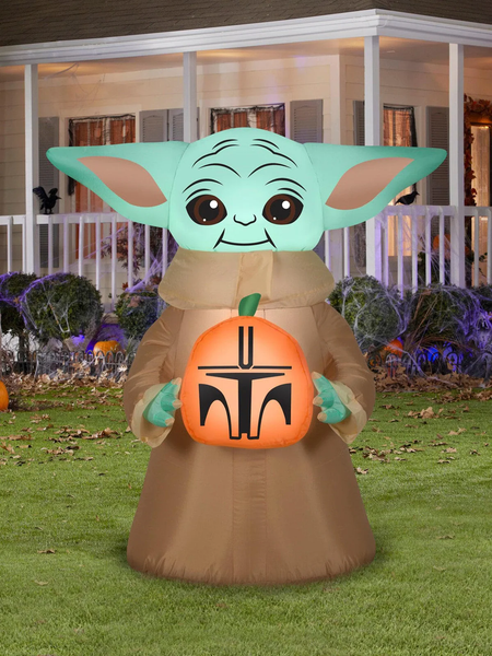 An inflatable Halloween decoration featuring Baby Yoda holding a jack-o-lantern with the Mandalorian's symbol.