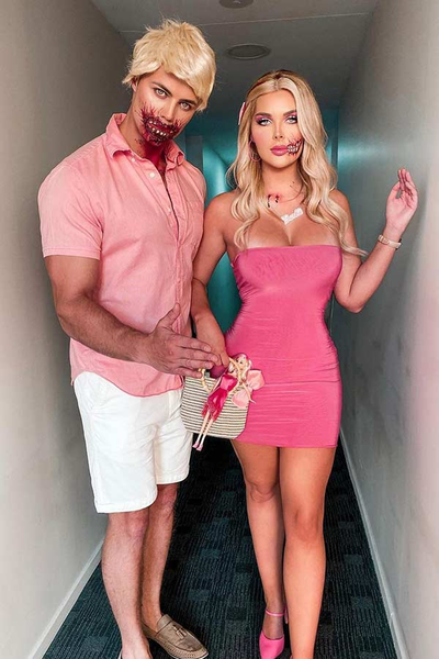 A couple wears a scary Barbie and Ken Halloween costume in matching pink outfits and special-effects makeup on their faces.