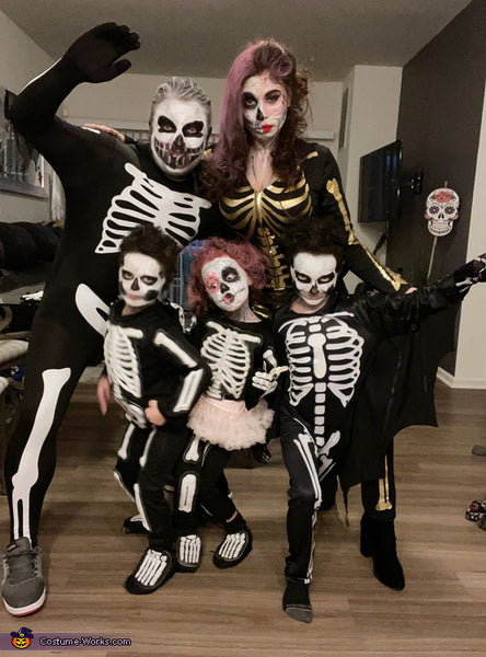 A family dressed in skeleton halloween costumes with makeup, wigs, and face paint.