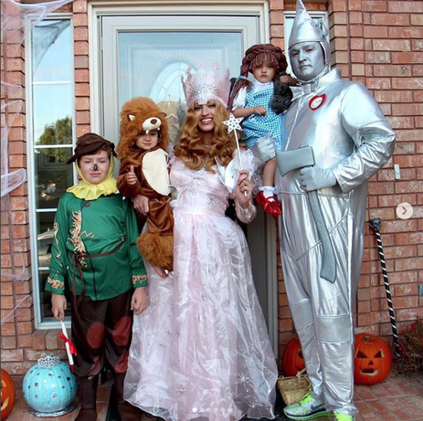 A family dressed in a Wizard of Oz themed Halloween costume, featuring Scarecrow, the Cowardly Lion, Glinda, Dorothy, and Tin Man.