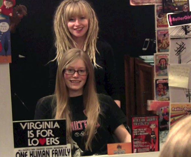 mirror shot of satisfied customer with long blonde straight hair smiling with hairstylist standing behind her both admiring the transformation