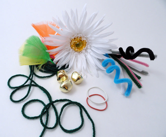 array of various items string elastics, cord, bells, plastic flowers and fuzzy twirly things on a white background