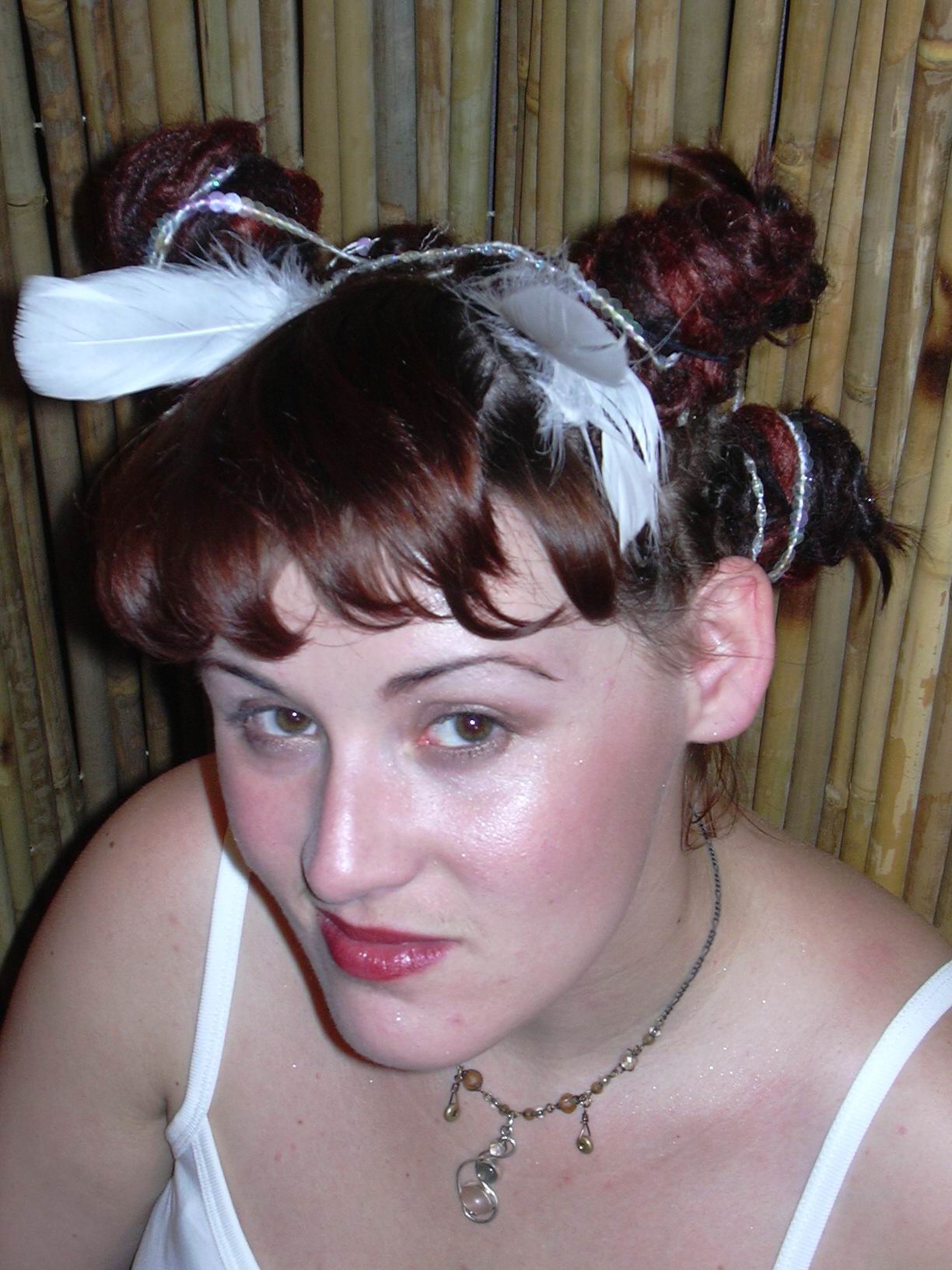 woman smiling slightly up at camera showing front view of hairstyle featuring tightly wrapped buns of dreadlocks