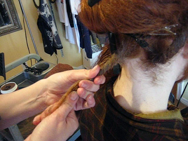 waxing a newly created dreadlock in long red hair