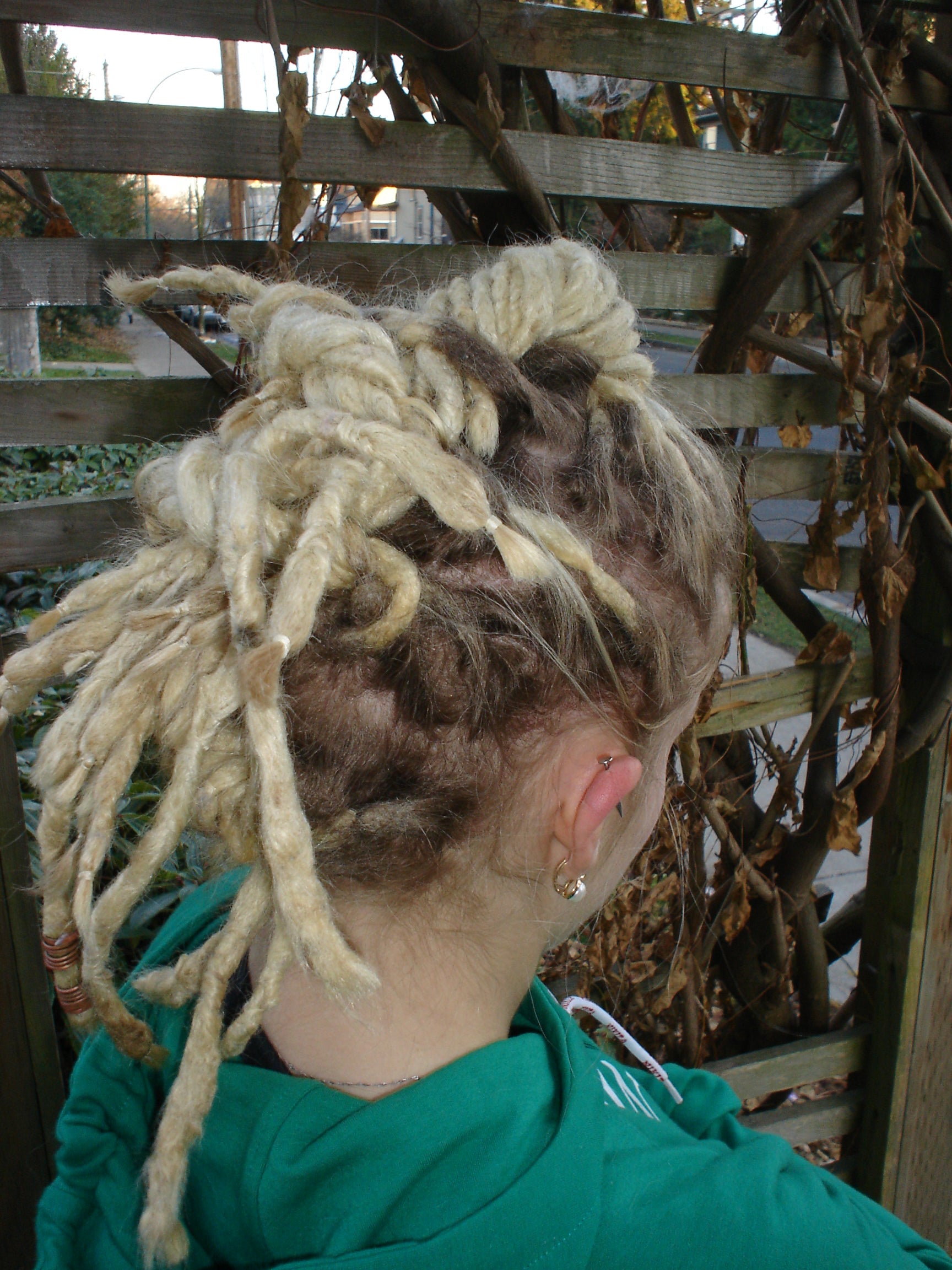back view of lock hawk hairstyle modelled by young woman in front of trellis
