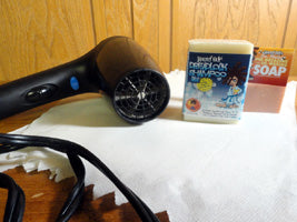 blow dryer, dreadlock shampoo bar, paper towels, and pre-dreading shampoo bar on a table
