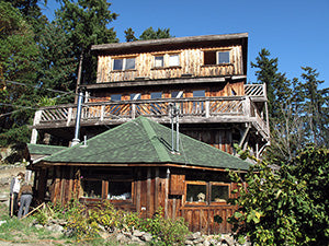 unusual house of many different styles on partially rocky ground surrounded by trees on a sunny day