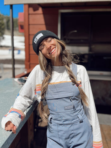 Girl wearing a ski and snowboard outfit smiling at a ski resort.