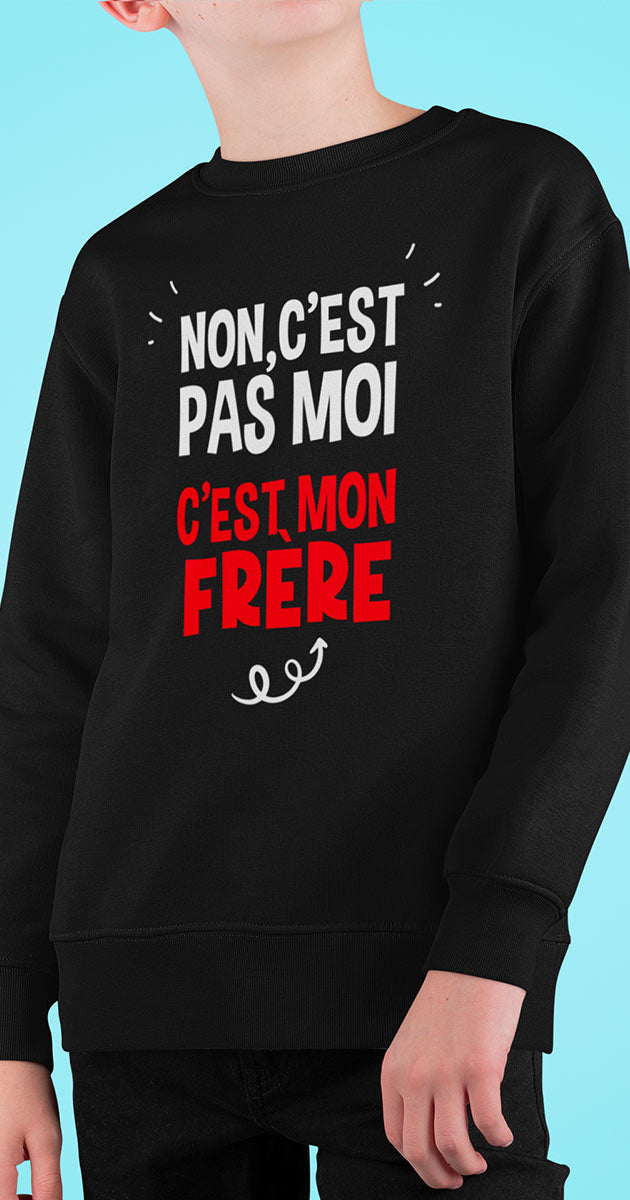 Garçon souriant, montrant fièrement l'inscription "C'est pas moi, c'est mon frère" sur son sweat