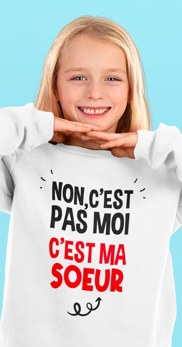 sœur riant, l'enfant portant le pull "C'est pas moi, c'est ma sœur"