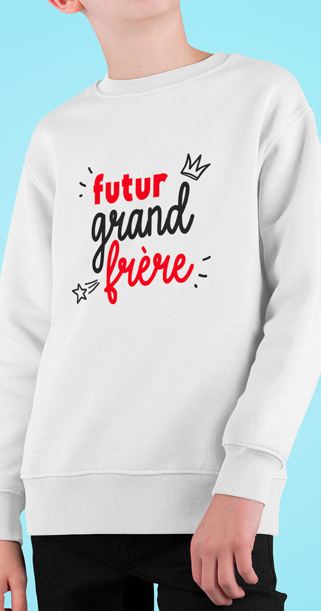 Petit garçon souriant avec éclat, portant son pull "Futur Grand Frère"