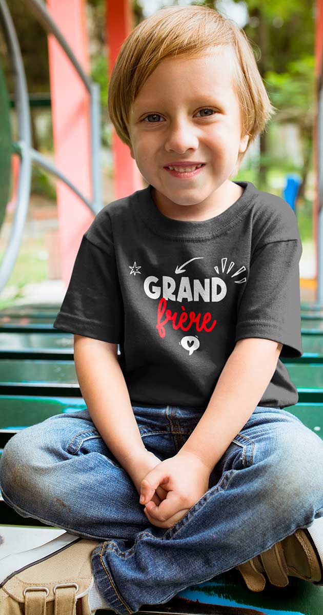 Garçon souriant portant fièrement son t-shirt "Grand Frère" en jouant