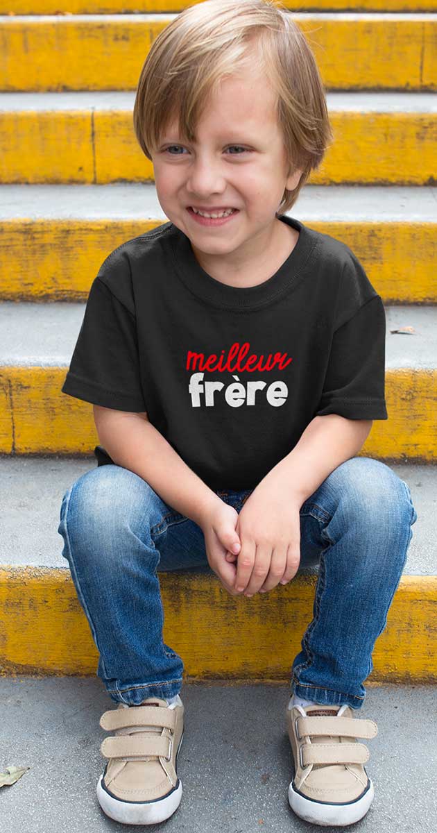 Grand frere souriant, portant le t-shirt "Meilleur Frère" sur des marches