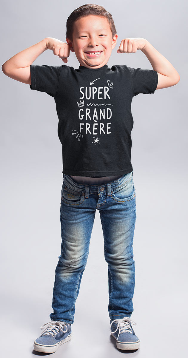n garçon souriant fièrement, portant le t-shirt "Super Grand Frère" avec une posture héroïque