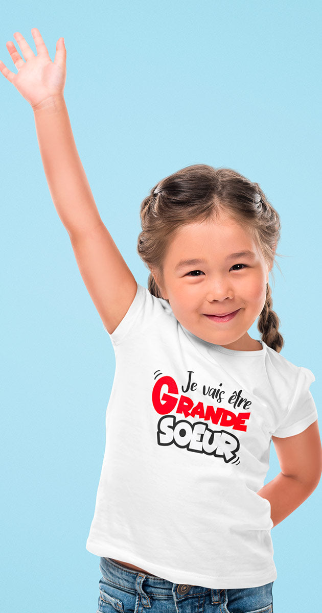 Petite fille souriante dans son nouveau t-shirt "Je vais être grande sœur"