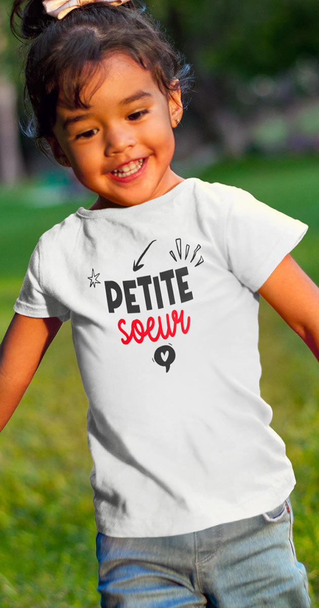 Petite fille rayonnante portant le t-shirt "Petite s%u0153ur" avec un grand sourire
