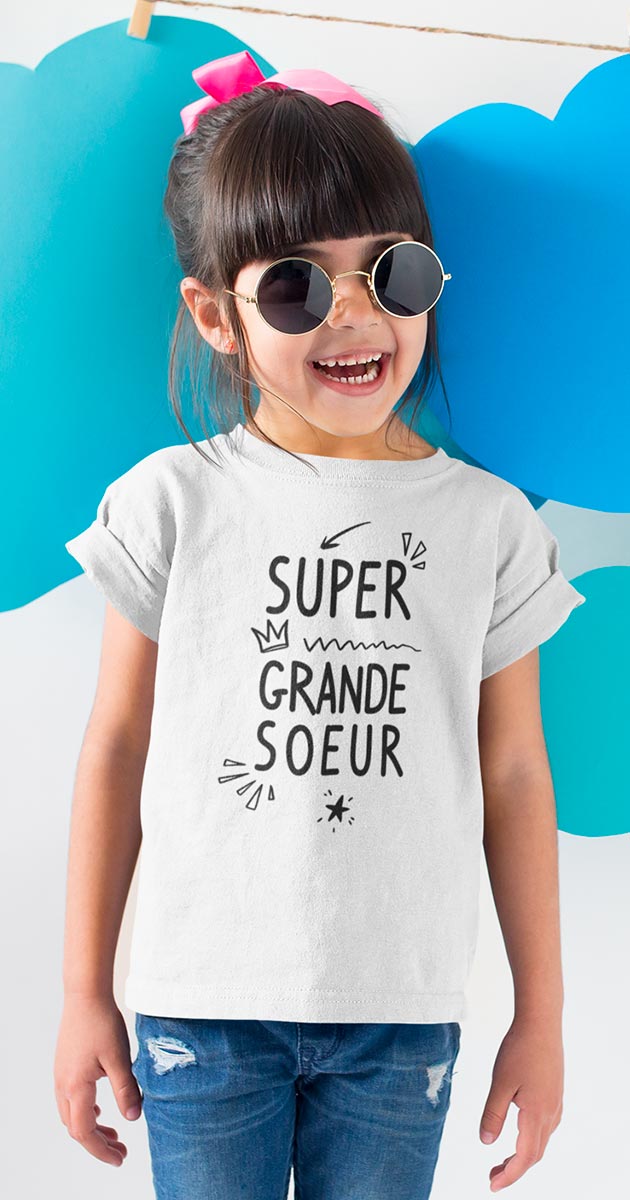 Fille souriante arborant fièrement son t-shirt "Super Grande Sœur"