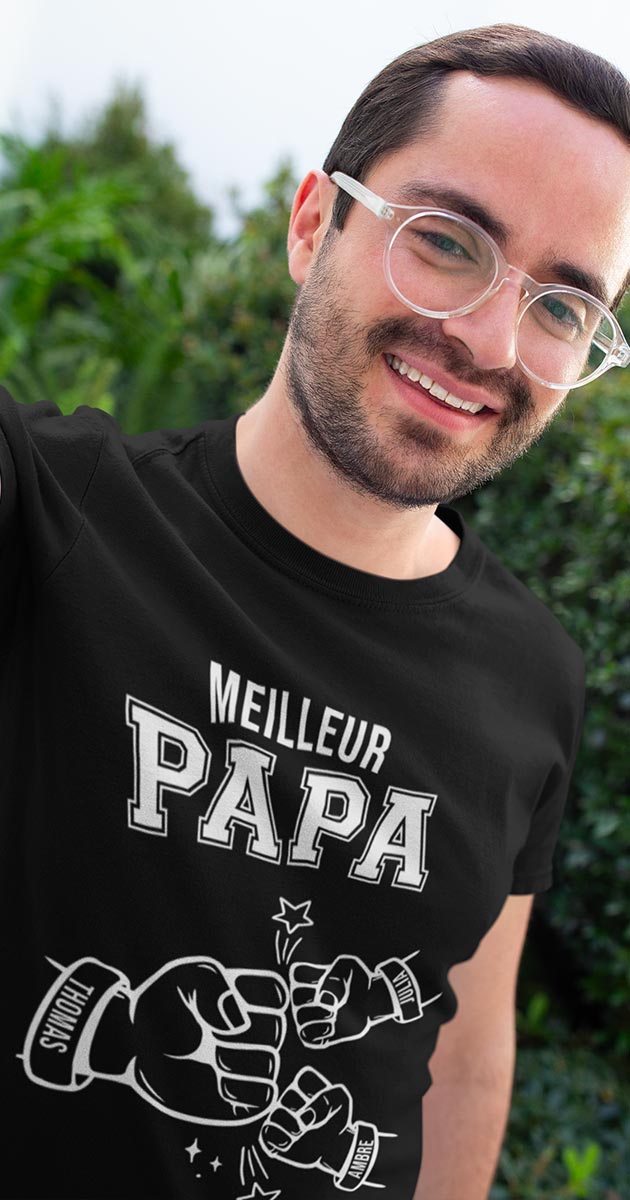 Papa rayonnant entouré de ses enfants, chacun pointant le T-shirt 'Meilleurs Papas' avec leur prénom inscrit.