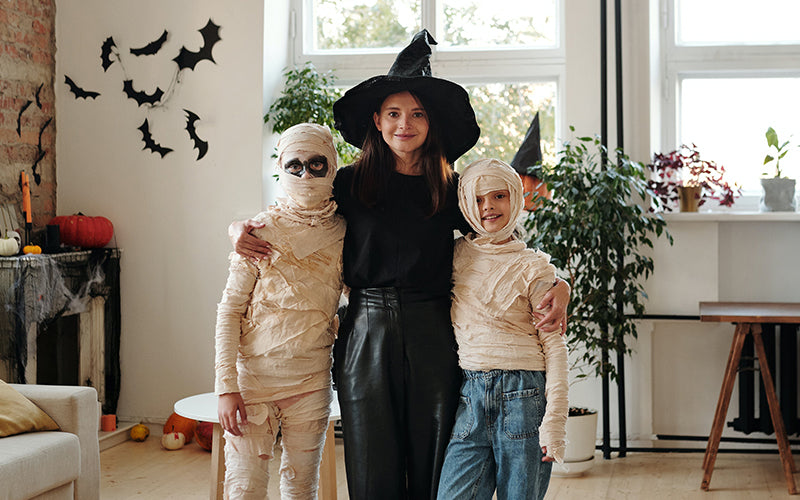 Image of two children dressed as mummies with their mother in a witches outfit