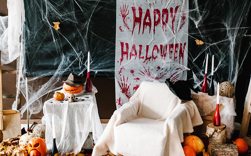 Image of a halloween scene in a livingroom styled with a blanket over chair