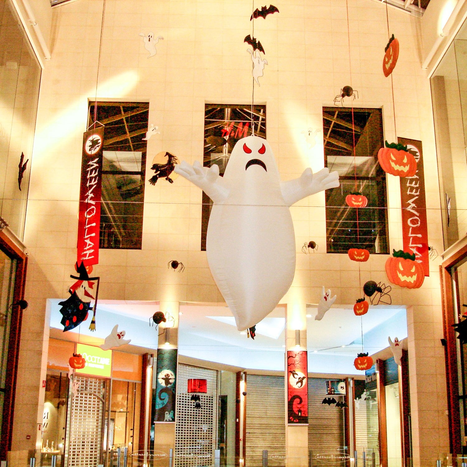 A giant inflatable ghost decoration hangs in a shopping mall Halloween display.
