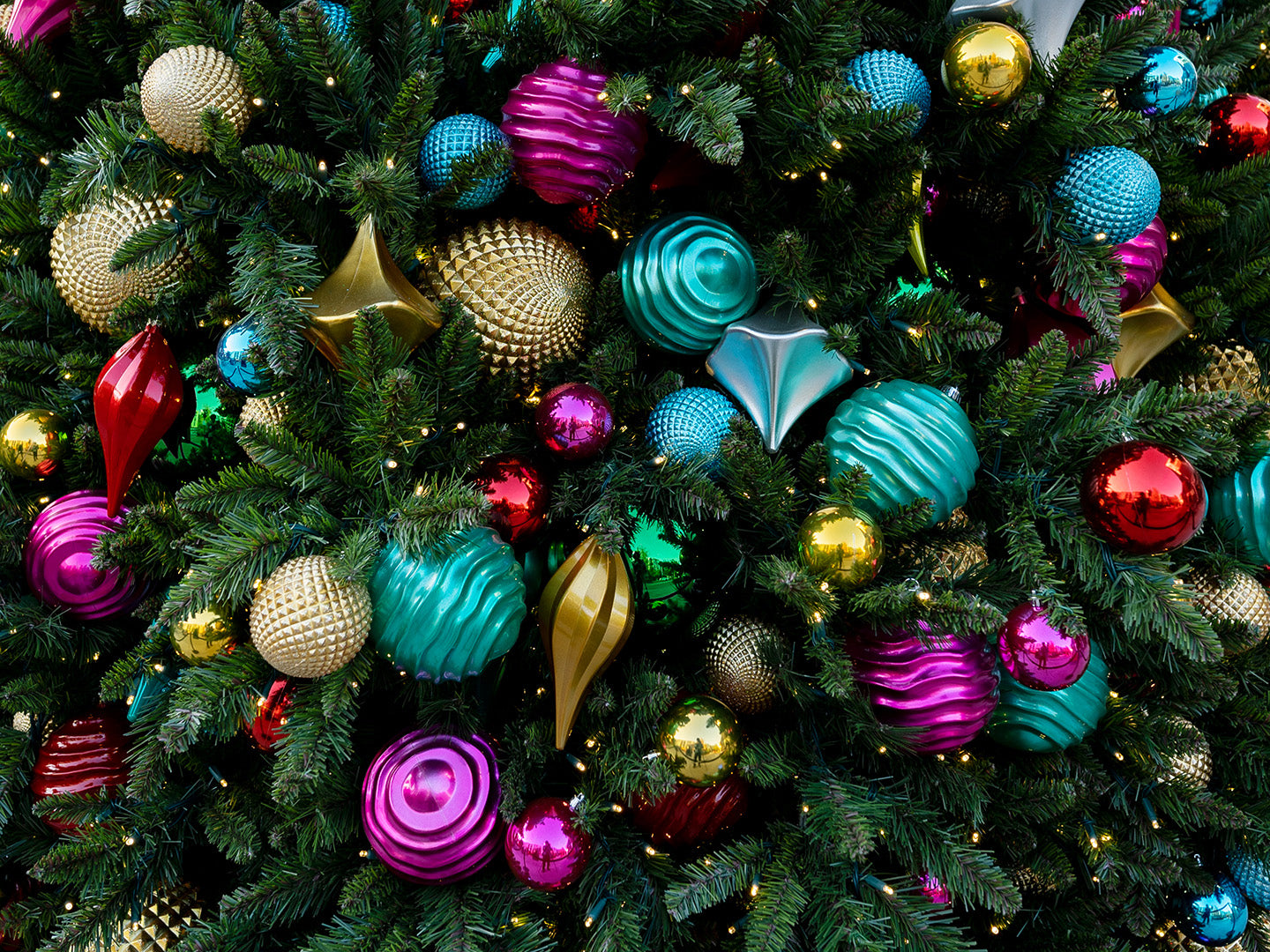 A vibrant Christmas tree bursting with brightly colored ornaments and shimmering lights.