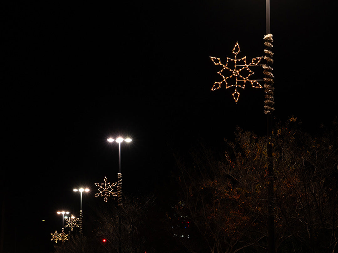 A row of street lights decorated with snowflakes, casting a warm glow on a winter night.