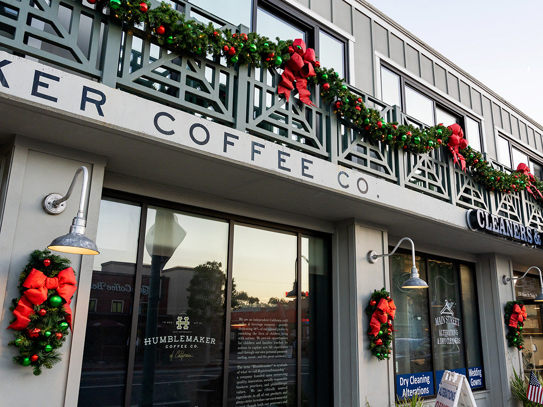 A storefront decorated for Christmas with a wreath and garland above the windows.