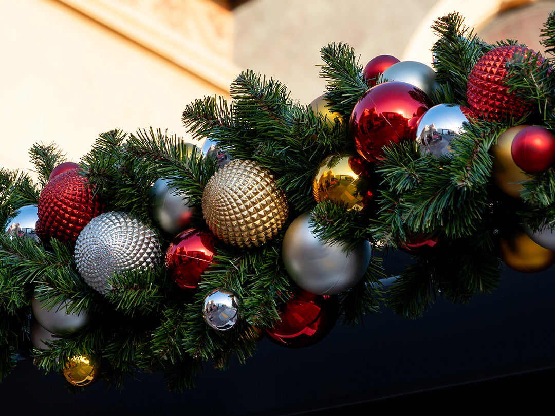 A festive Christmas garland with various red, gold, and silver ornaments.