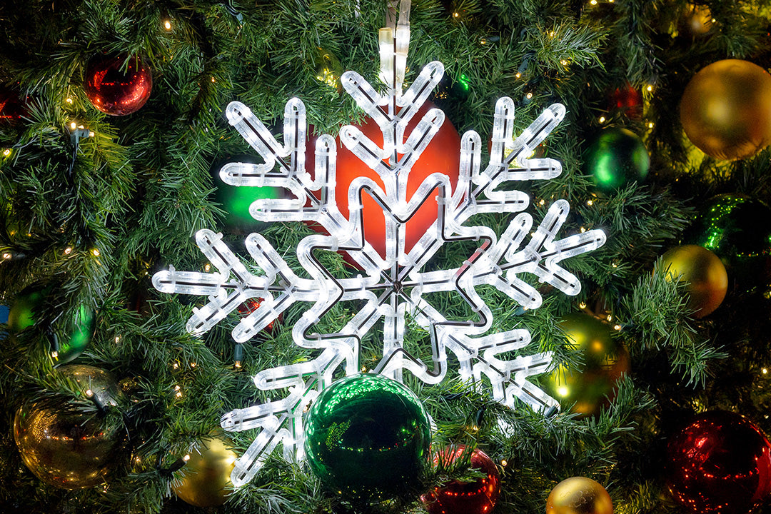 A Christmas tree decorated with red, green, and gold ornaments, topped with a snowflake.