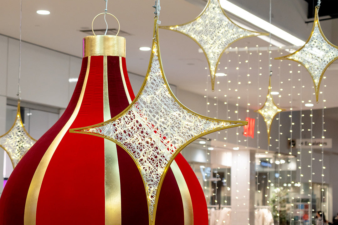 A vibrant Christmas scene in a shopping mall, with colorful ornaments, snowflakes, and lights hanging from the ceiling.