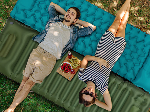 A couple lying on top of the aksoul self-inflating connectable sleeping mat to enjoy the sun