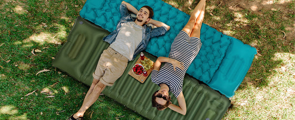 Couples lying on top of the AKSOUL self-inflating sleeping mat that can be connected together to see the sky