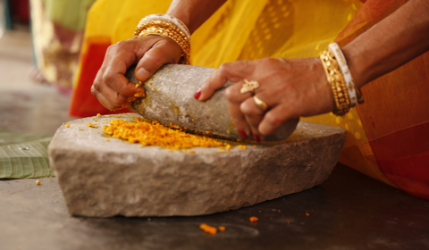 Woman grinding turmeric for skincare