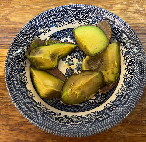 bruised avocado cut into chunks put on blue and white place with wood background