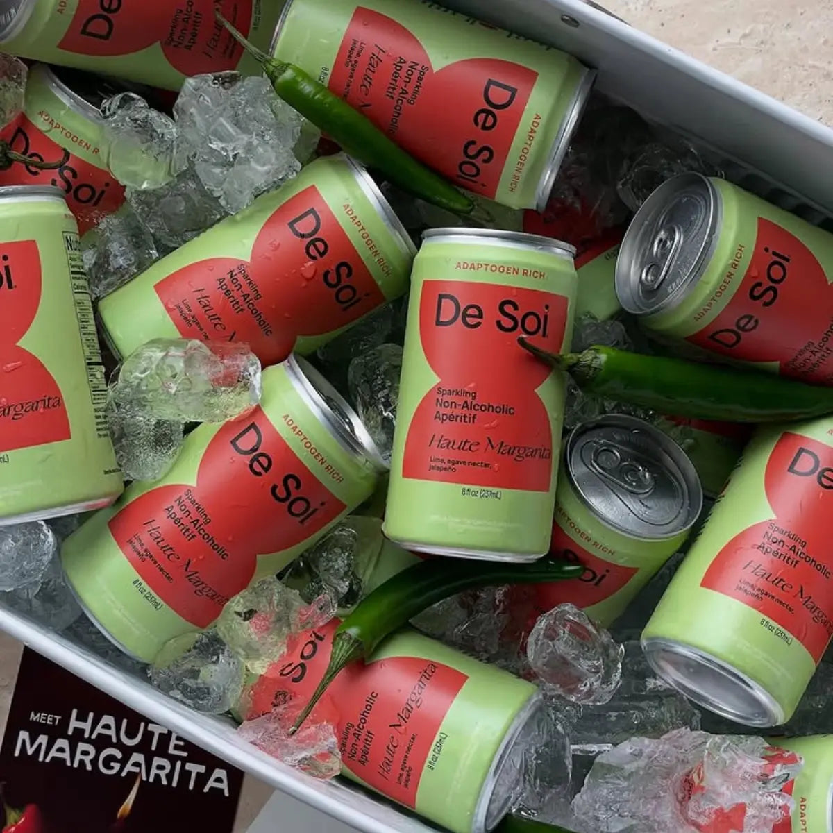 Non-alcoholic aperitif De Soi cans in ice with green chili peppers and product brochure.