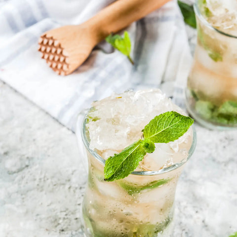 Close-up of Mint Julep mocktail with crushed ice and mint garnish next to a wooden muddler