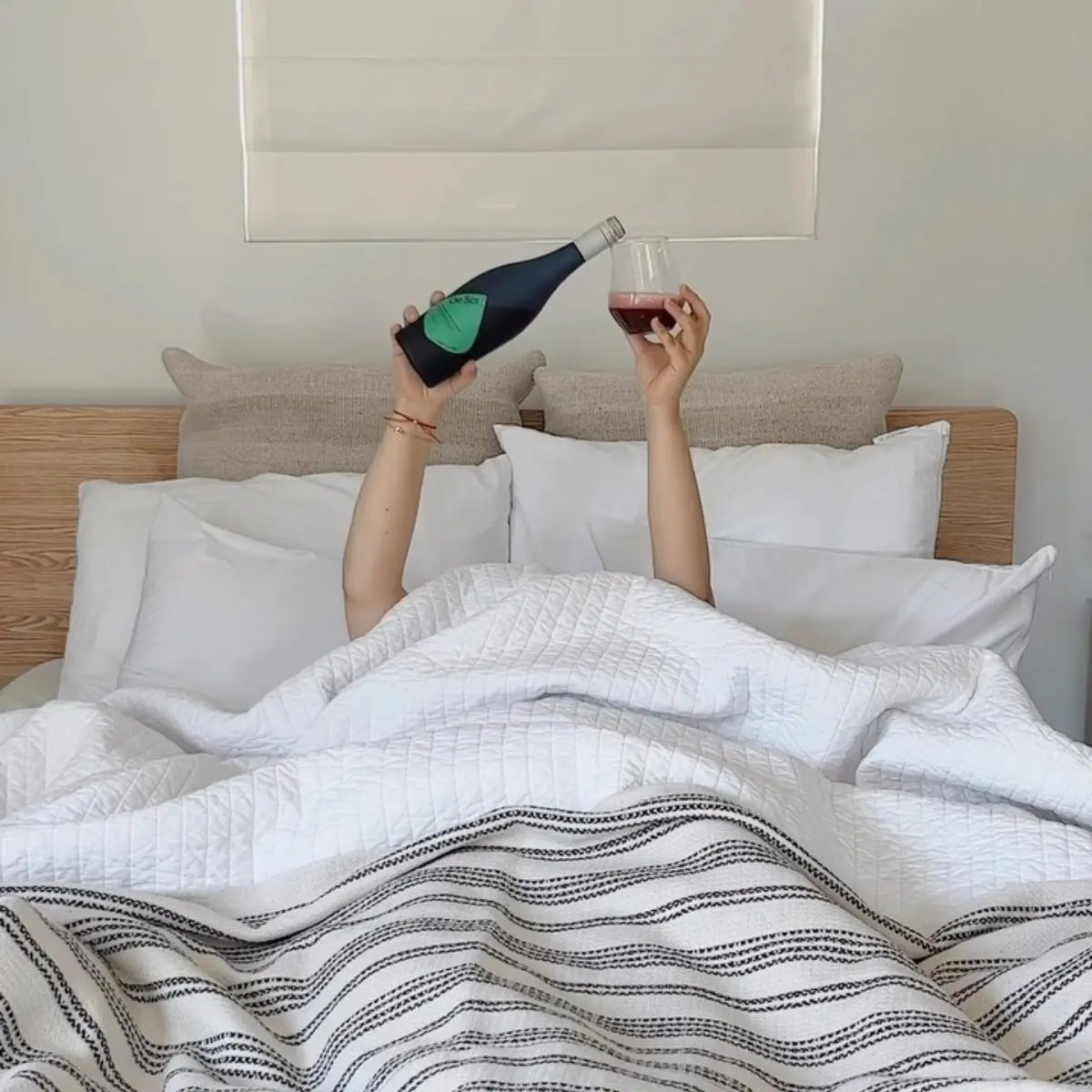 Functional mushroom drink poured in bed from a De Soi bottle into a glass, emphasizing relaxation and wellness.