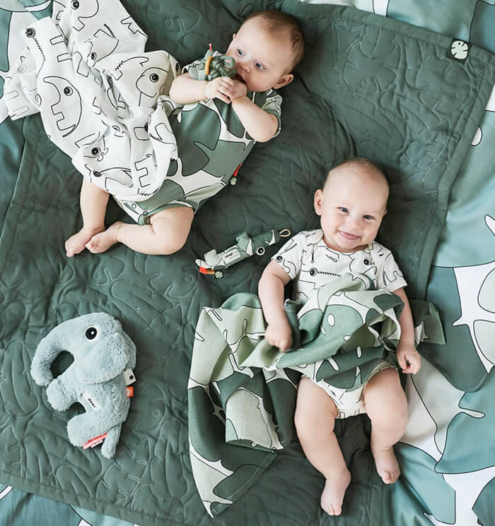 Babies playing with activity toys in green from Done by Deer