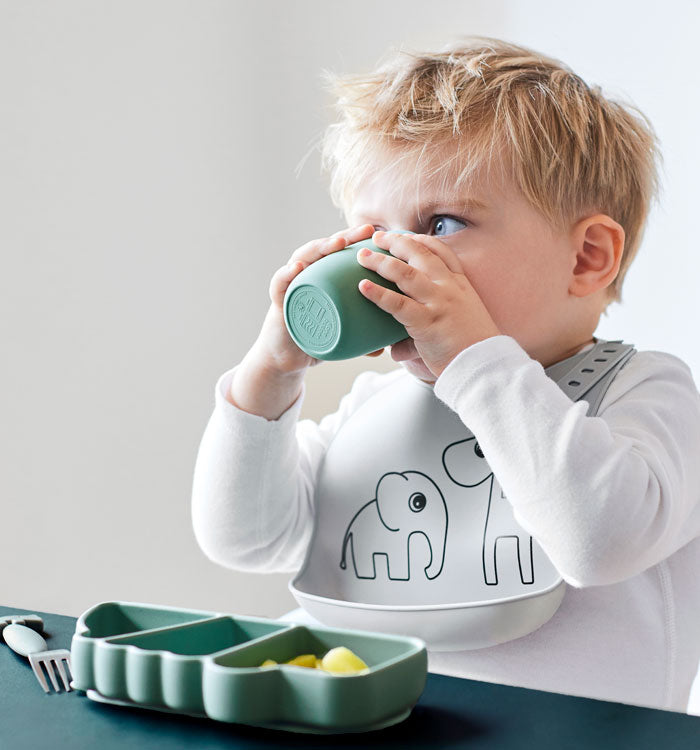 Boy drinking an eating from silicone tabelware set