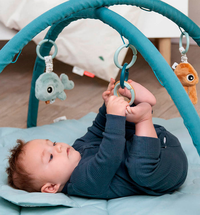 Baby playing with toys on a Done by Deer activity play mat