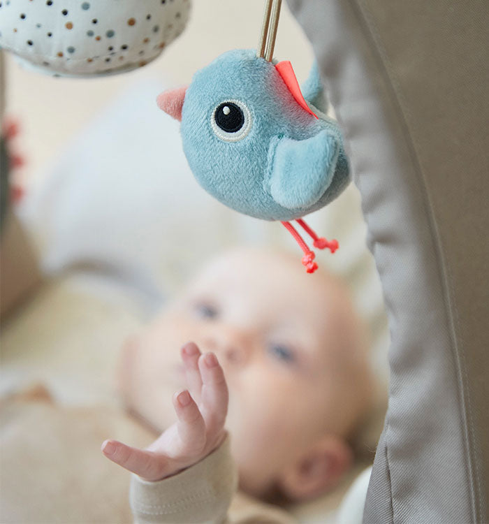 Baby reaching for bird on the Done by Deer activity arch