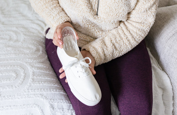 Person placing Foot Petals air gel heel cup into clean white sneaker