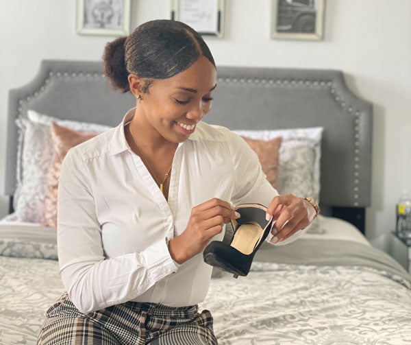 woman placing back of heel cushion into black high heels