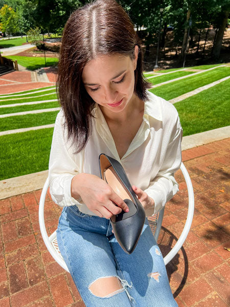 Woman placing black ball of foot cushion in black heel