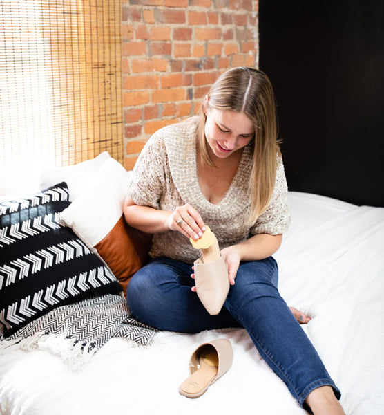 Woman placing Foot Petals shoe cushion inside beige slip on shoe