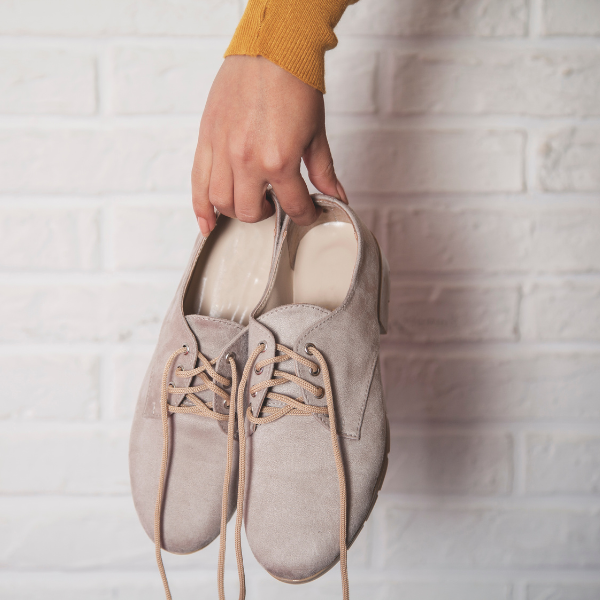 woman holding beige suede dress shoes