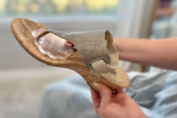 Woman placing ball of foot cushion for sandals inside sandal