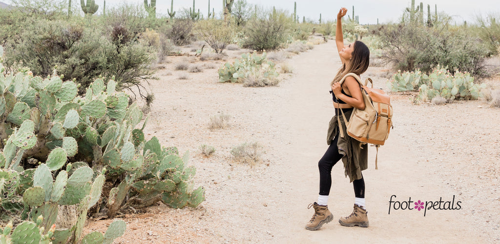 Woman wearing hiking outfit in desert looking at sky