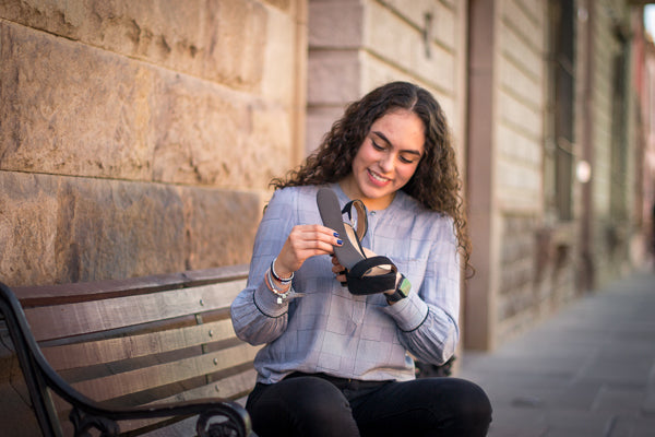 Woman sitting on bench putting black shoe insert into black heel